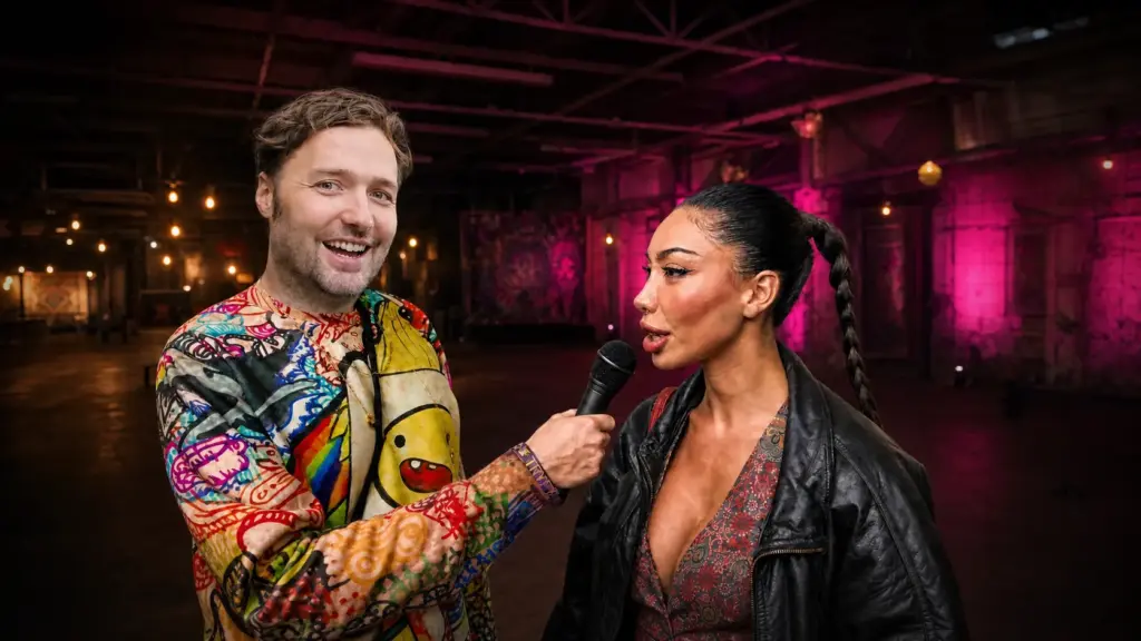 Simon interviewt eine Besucherin auf der TRYP Expo in Berlin vor magenta beleuchtetem Messehintergrund